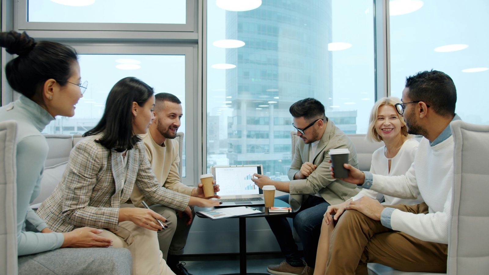 A diverse team discussing charts on a laptop in a modern office lounge