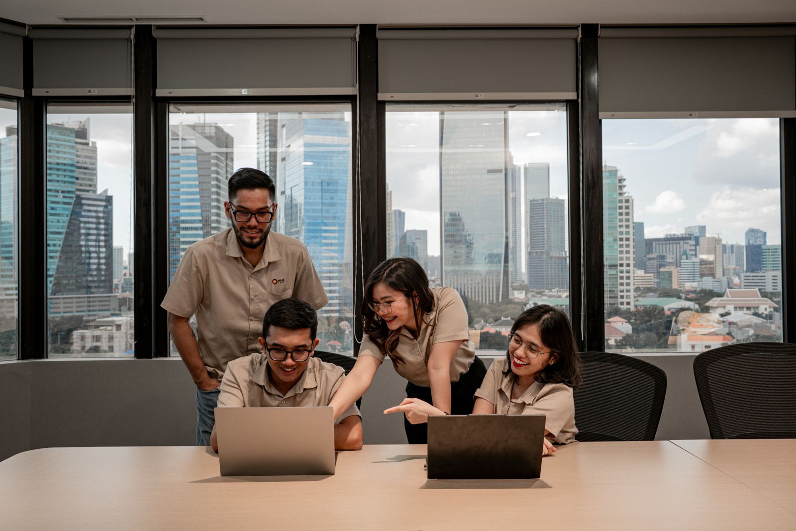 Four colleagues gathered around laptops in a bright city office